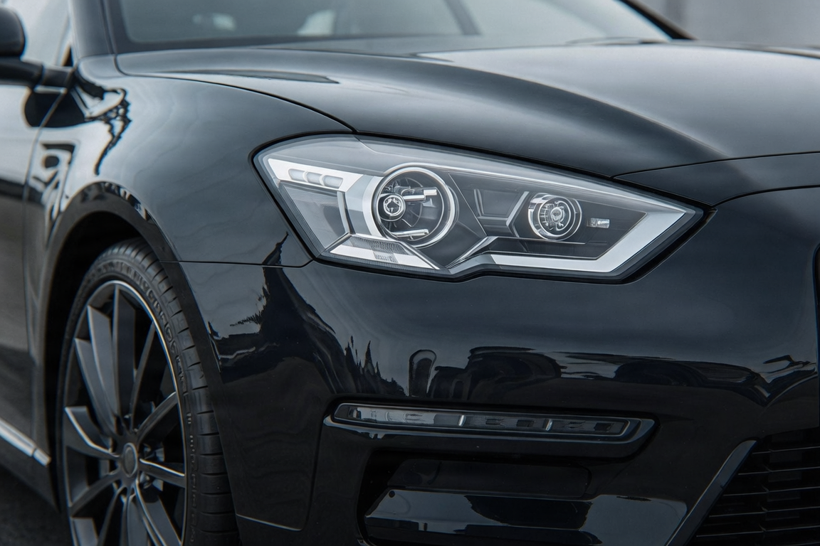Close-up of a car's front bumper with clear paint protection film applied, showing invisible protection.
